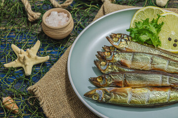 Smoked smelt with fresh lemon and herbs. Salted fish with marine decor. Trendy dish, sea rope