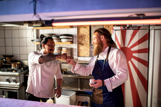 Two chefs fist bumping in Japanese restaurant kitchen teamwork moment