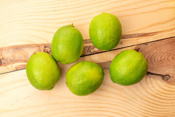 Sour juicy limes on a wooden table, close-up, top view.
