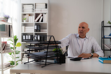 Three asian businesswomen leaning on a desk and arguing about negative financial results showing on some documents during a late night meeting in the office