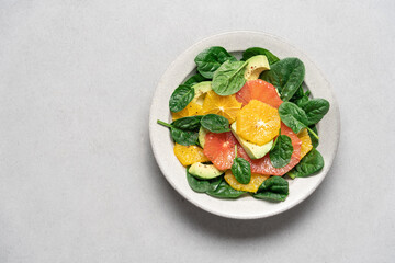Fresh grapefruit avocado orange spinach salad in bowl. Healthy salad on gray background top view