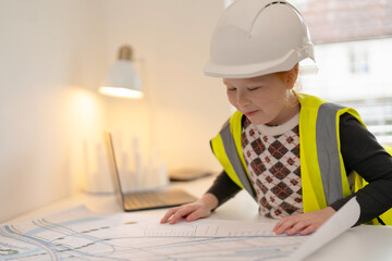 Young child engaged in a creative building activity in bright room while wearing safety helmet and...