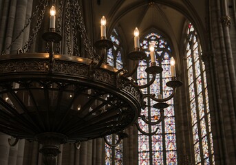 Ornate chandelier glows softly in gothic cathedral. AI Generated