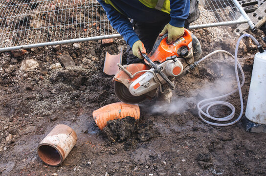 Builder cutting through clay pipe at construction site