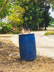 Legs and shoes of old dirty female mannequin were thrown into blue trash can on roadside with the...