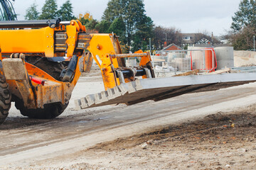 Forklift telehandler lifts concrete beams on construction site