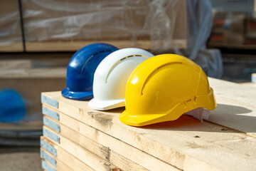 Construction helmets of different colors arranged on wooden scaffold boards 