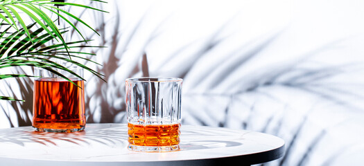Irish blended barley whiskey n glass with bottle on dark green background, hard light with palm...
