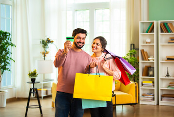 Indian couple shows happiness after shopping, standing together with shopping bags indoors