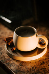 Warm cup of coffee with cinnamon sticks on a cozy kitchen countertop in soft lighting