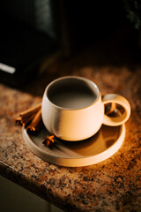 Warm cup of coffee on a cozy countertop with cinnamon sticks nearby during morning light