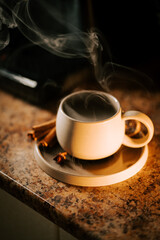 Warm cup of coffee surrounded by cinnamon sticks on a cozy countertop in a kitchen