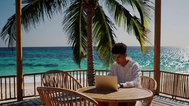 Man working on laptop outdoors seated under palm trees with turquoise ocean background bright sunny tropical day remote work lifestyle digital nomad freedom career beach