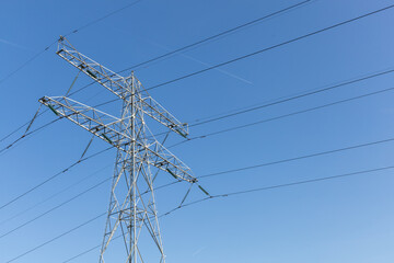 High-voltage power line and transmission tower against a clear blue sky, symbolizing energy, infrastructure, and electricity supply in the Netherlands.