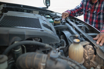 The man is checking the engine and condition of car to fix it properly and safely before traveling long distances. The man is checking condition of the car and the engine before traveling for safety.