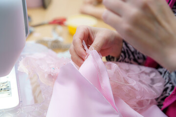 Sewing delicate fabric for a custom dress in a workshop environment on a bright afternoon