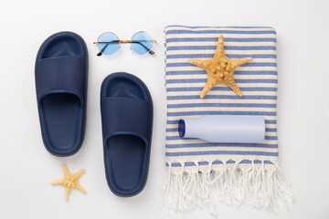 Beach towel with summer accessories on color background, top view