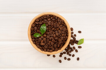 Roasted coffee beans with leaves on wooden background,top view