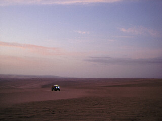 Solitary car at dusk in the desert - cinematic retro photo.