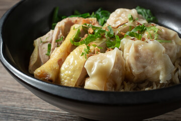 A closeup view of a bowl of wonton noodle soup.