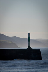 the light at aberystwyth harbour on a misty sunny morning
