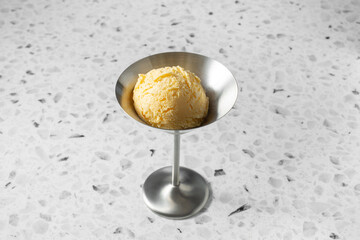 A view of a scoop of vanilla ice cream in a metal martini glass.