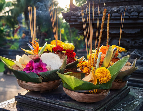 Traditional Balinese offerings (canang sari) with colorful flowers and incense are displayed, representing spiritual practices and daily rituals.