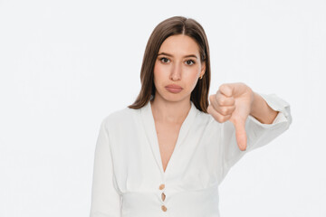 Headshot of young woman showing finger thumb down as refusal sign. Studio portrait of unhappy...