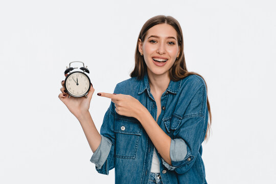 Young Smiling woman girl manager student holding pointing index finger on round clock isolated on white color background studio portrait copy space. People sincere emotions lifestyle concept.