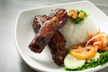 A view of a plate of pork back ribs, with white rice.