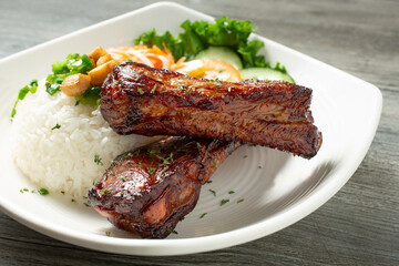 A view of a plate of pork back ribs, with white rice.