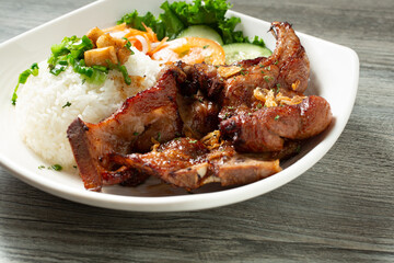 A closeup view of a plate of pork chops, with white rice.