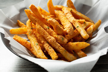 A view of a basket of french fries, topped with cheese powder.