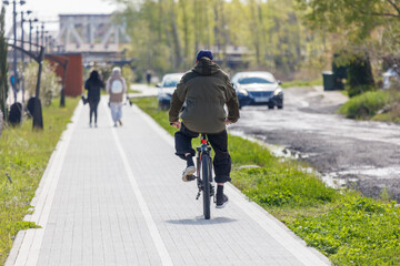 Obraz premium A man rides a bike down a sidewalk next to a road
