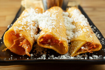 A closeup view of a plate of taquitos.