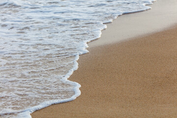 The ocean waves are crashing onto the shore, creating a beautiful