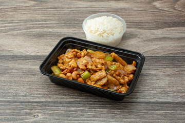 A view of a container of cashew chicken, with white rice.