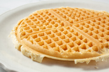 A view of a plain waffle, on a plate.