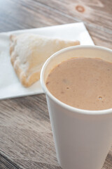 A view of a cup of champurrado, with a pan dulce.