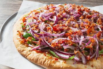 A closeup view of a bacon veggie pizza.