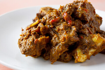 A closeup view of a plate of curry goat meat.