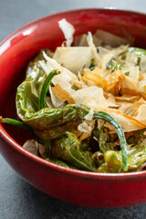 A closeup view of a bowl of shishito peppers.