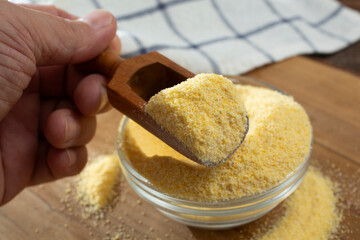 A view of a hand scooping some cornmeal.