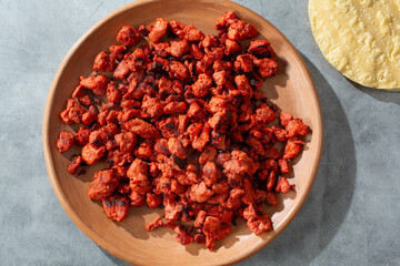 A top down view of a plate of chopped al pastor taco meat.