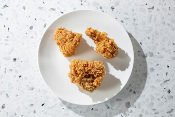 A top down view of some extra crispy fried chicken pieces, on a plate.