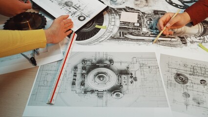 Engineers collaborate on technical drawings and mechanical schematics, showcasing hands-on teamwork...