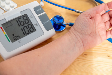 woman's hand with blood pressure monitor on wooden table, healthcare device, health check, medical...