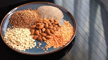 Vegan ingredients like almonds, oats, buckwheat, chia seeds, lentils on display. Sustainable, eco-friendly essentials for nutritious plant-based diet supporting health and planet. Vegan food