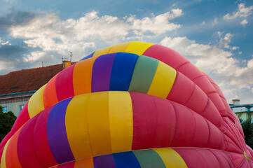 fragment of a dome, a multi-colored balloon inflates against a background of the sky with clouds