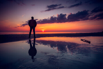 Rear view silhouette of a man standing on a beach by the Baltic Sea at sunset, Lithuania